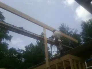 Carpenter setting a ridge beam over a new addition frame — Ice Dam Removal by Roofing Brothers in Alton Bay