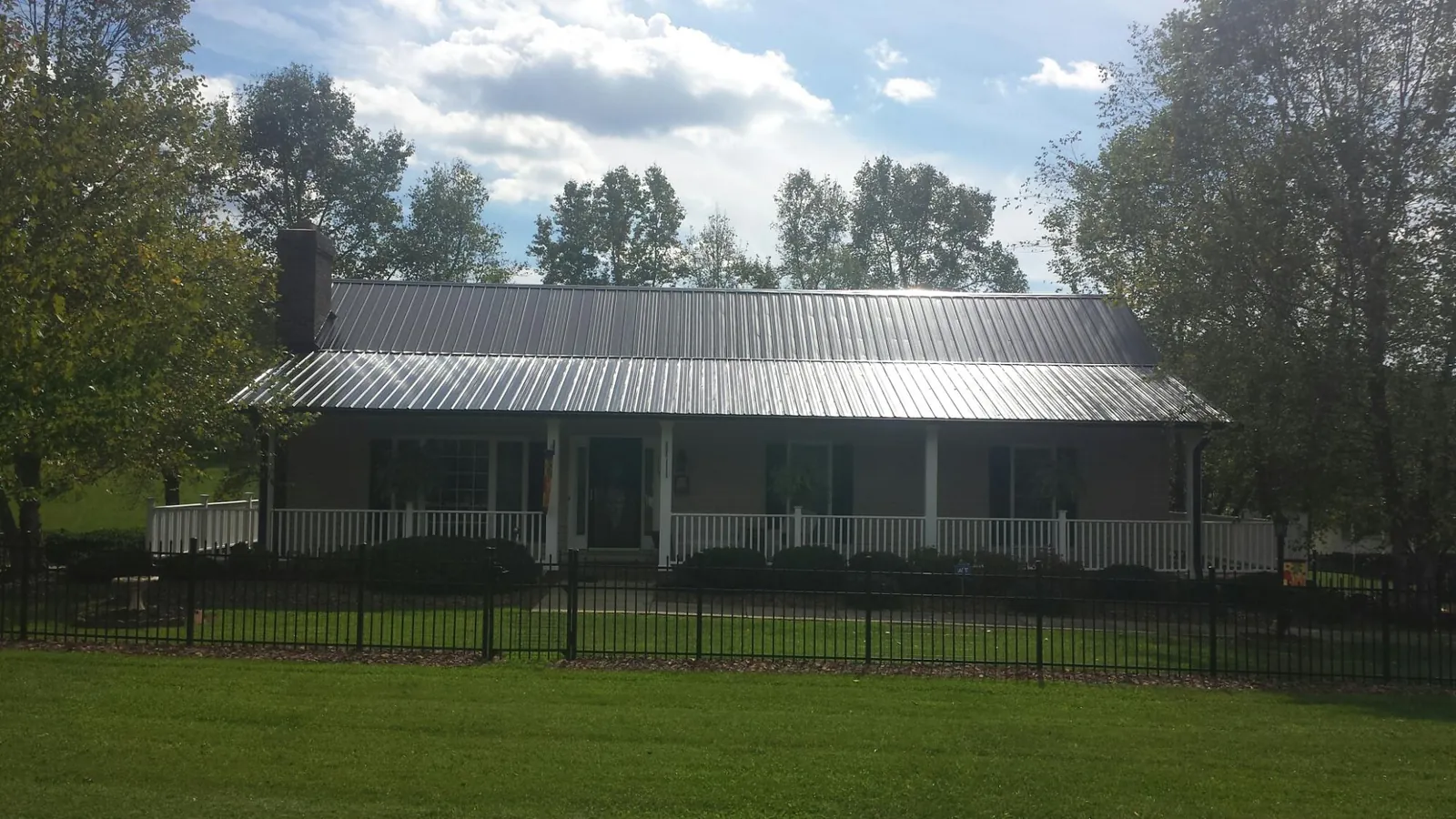 Gray metal roof on a brick ranch with a full width front porch — Gutter Guard Installation work by our crew in Alton Bay