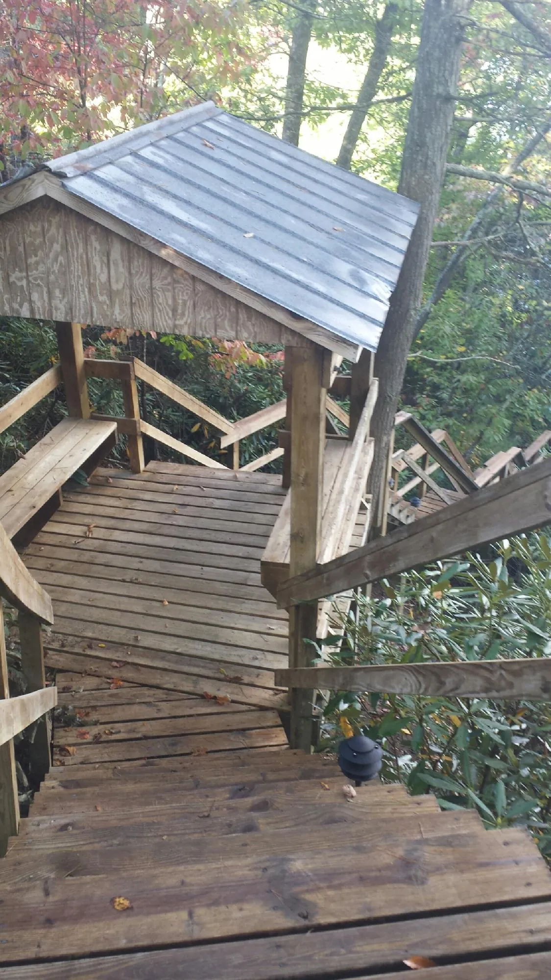 Metal roofed shelter over wooden steps on a wooded walkway — Skylight Repair & Installation work by our crew in Alton Bay