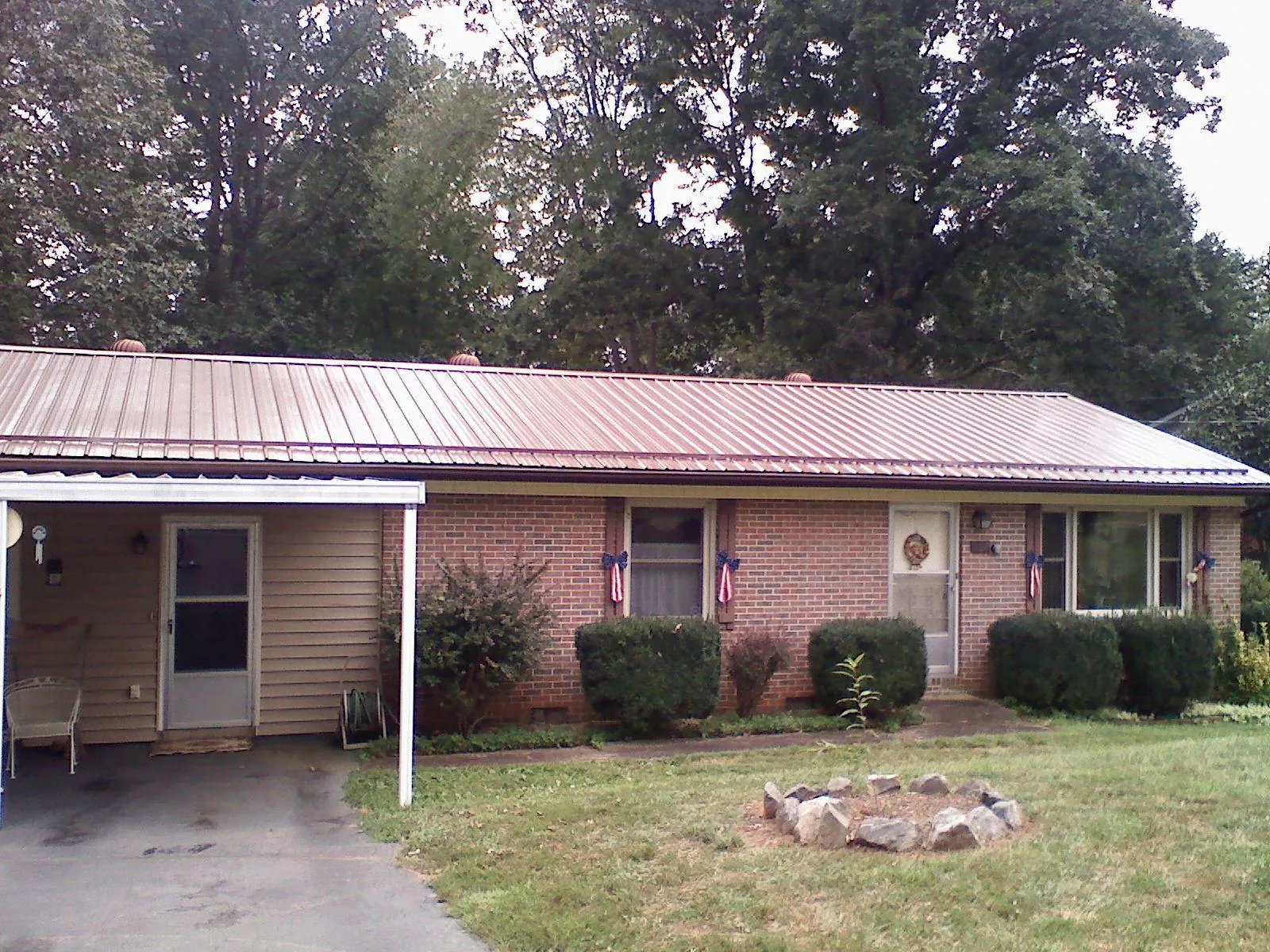 Bronze metal roof and carport on a brick ranch home — Roof Repair work by our crew in Alton Bay