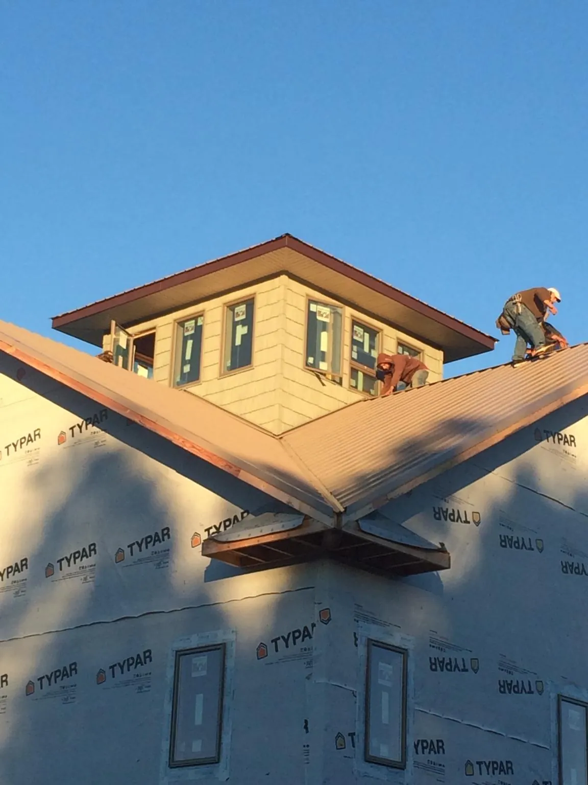 Roofers working around a rooftop cupola on a new metal roof at sunset — Roof Waterproofing in Alton Bay by Roofing Brothers
